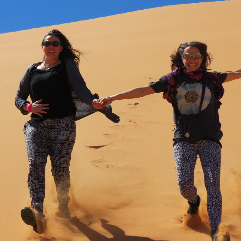 women running down a dune in the sahar desert, morocco