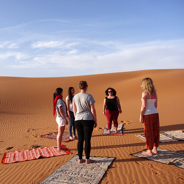 women standing in a circle in the sahar desert for yoga, meditation, dance, morocco