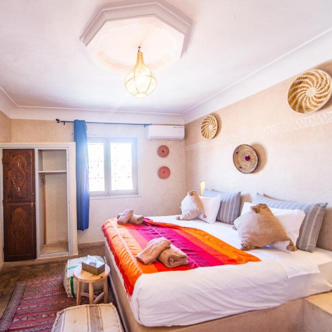 single room in marrakesh riad in morro, with decor on the walls and an orange blanket on top