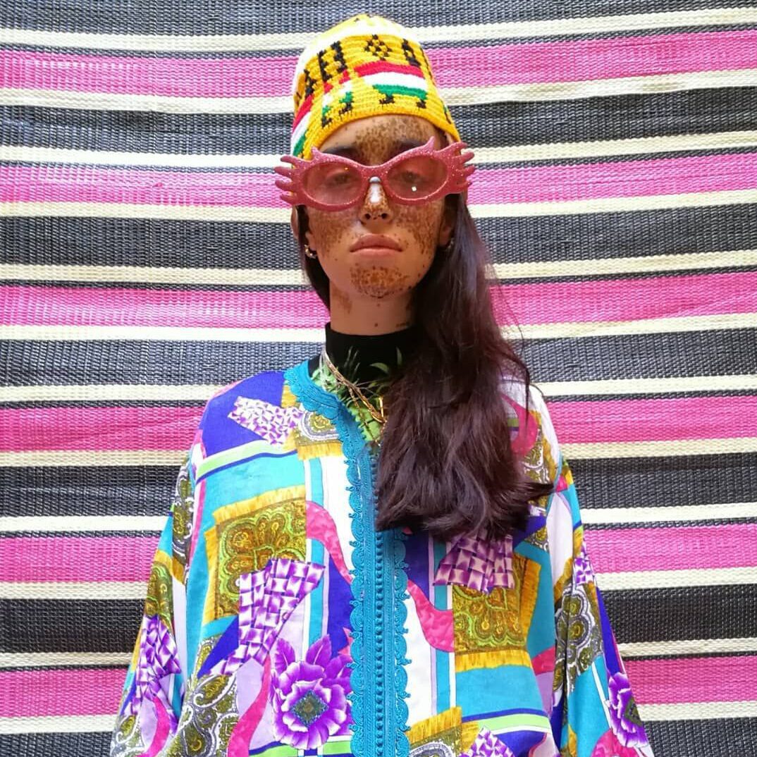 woman in modern arabic fashion style, with colorful blouse, yellow hat and fancy sunglases