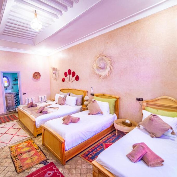 triple room in marrakesh with three wooden beds and a wooden wardrobe