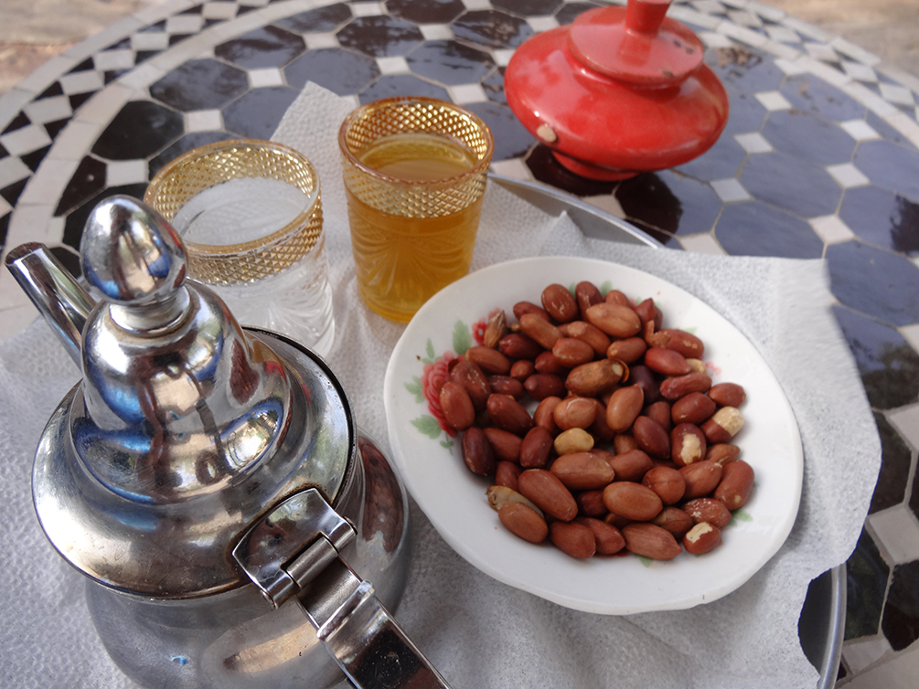 Moroccan Mint Tea and peanuts on a plate and a red ashtray with a lid on a ceramic table, Sahara Desert, Erg Chebbi